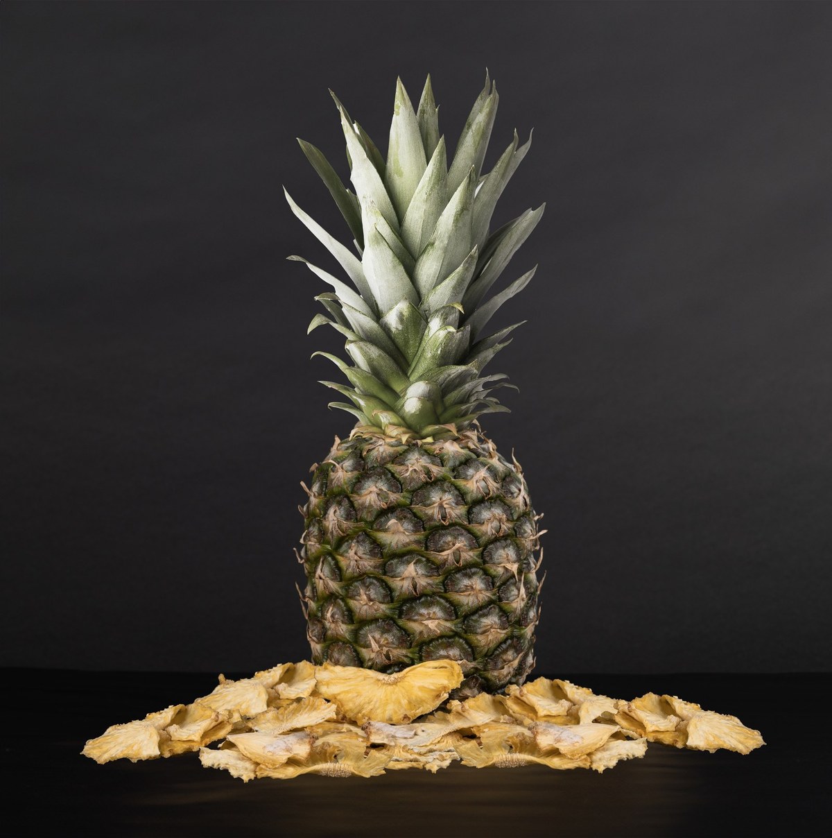 Fresh pineapple with dried slices, studio black background